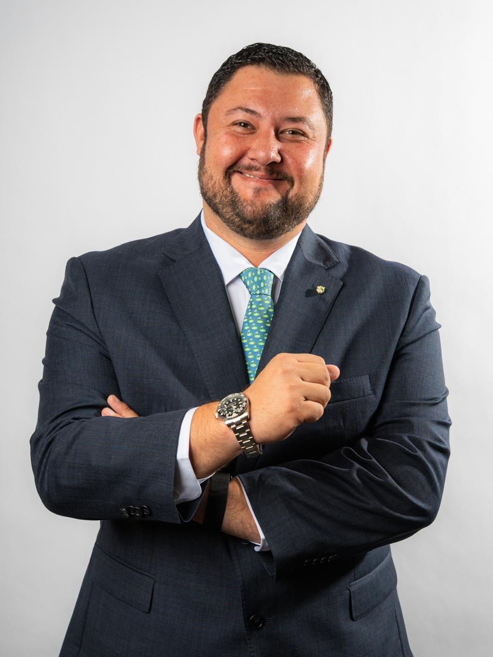 Raúl Zamora sonriendo, de traje y corbata turquesa